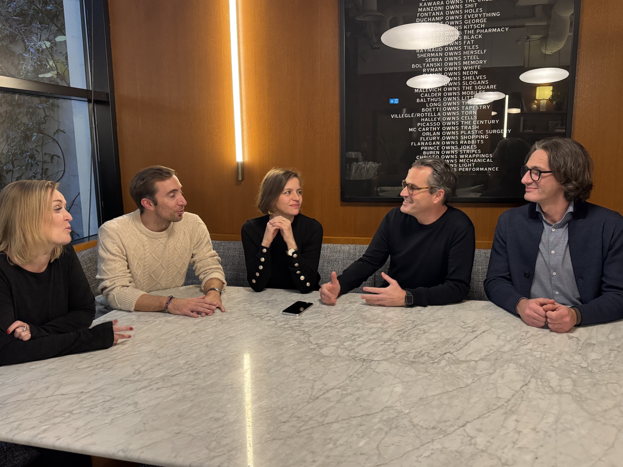Members of the Selected4You team talk around a table at Le Bureau
